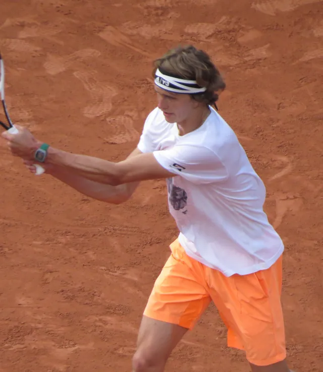 Alexander Zverev in Weiß und orangefarbenen Shorts trainiert eine Rückhand auf Sand in Roland Garros 2017